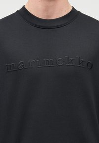 Μαύρο φούτερ από μαλακό ύφασμα με ανάγλυφο, ανάγλυφο λογότυπο "marimekko" στο στήθος. Λαιμόκοψη crew, casual εφαρμογή.