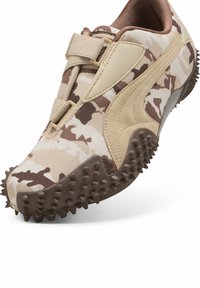 Sneaker met beige en bruine camouflage-stof, beige suède accent, klitngesluiting en bruine zool met grote, gestructureerde rubberen spikes.