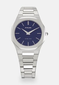 Montre en acier inoxydable argenté avec un boîtier octogonal, un cadran bleu marine, des index argentés et un design ultra-mince.