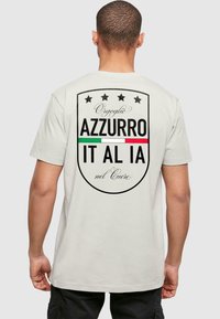 Light gray cotton t-shirt with a large printed design featuring text, five stars, and green, white, and red accents on the back.