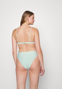 Conjunto de biquíni azul claro com padrão floral; apresenta alças ajustáveis e fecho de clipe nas costas. Textura de tecido suave.