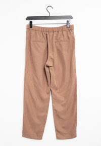 Pantalon marron à taille élastique avec deux poches arrière et une texture lisse, suspendu à un cintre noir sur un fond blanc.