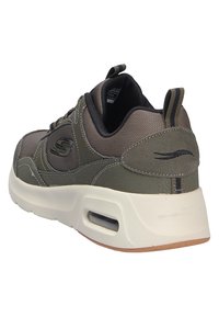 Scarpa sportiva verde scuro in materiali mesh e scamosciati, con colletto imbottito e suola intermedia bianca con ammortizzazione ad aria. Presenta un linguetta di estrazione e dettagli logo.