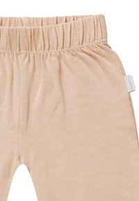 Lichtroze leggings gemaakt van zachte, gestructureerde stof. Voorzien van een elastische tailleband en een klein etiket aan de zijkant.