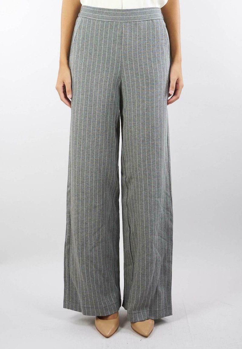 Pantaloni larghi grigi con righe blu, realizzati in tessuto morbido. Presentano un elastico in vita e una vestibilità comoda, abbinati a tacchi nudi.