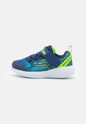 Baskets pour enfants Skechers bleues et vertes avec semelle blanche, lacets élastiques et bande Velcro, conçues pour la course et un usage décontracté.