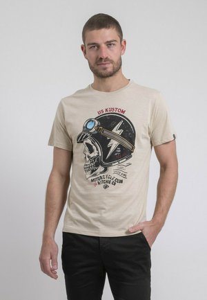 T-shirt en coton beige avec un graphique d'un crâne portant un casque de moto, avec le texte « US KUSTOM » et « MOTORCYCLE CLUB » en noir.