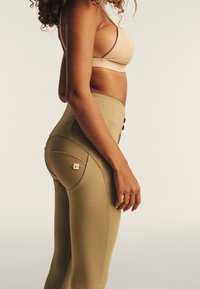 Leggings verdi oliva a vita alta con vestibilità aderente, dotati di una tasca posteriore accentuata da un piccolo marchio e dettagli di cucitura visibili.