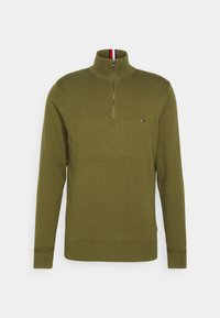 Pull en maille vert olive à manches longues avec col montant demi-fermeture éclair et petit logo rouge, blanc et marine sur la poitrine gauche.