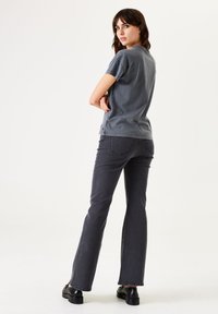 Camiseta gris de manga corta combinada con jeans acampanados gris oscuro y zapatos de plataforma negros. La camiseta tiene un corte holgado.
