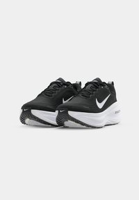 Juodi sportiniai batai su tekstūruotu paviršiumi, baltas "Nike" ženklas, masyvus baltas tarpinis padas ir raštuotas gumos padas.