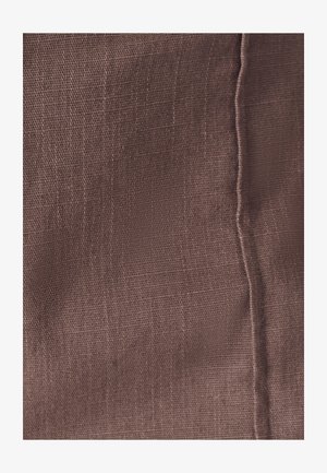 Tekstiili hillityssä ruskeassa sävyssä, jossa on teksturoitu pinta, hienovarainen kudottu kuvio ja näkyvä ompelu reunan varrella.