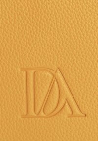 Superficie de cuero texturizado amarillo con las letras superpuestas en relieve "D" y "A" en el centro.