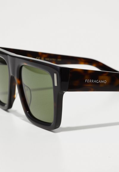 Mustad ja kilpkonnakilbiga ristkülikukujulised prillid roheliste läätsedega, mille raam on metallaktsentidega. Brändi nimi "Ferragamo" trükitud küljel.