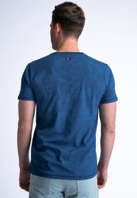 Blauwe t-shirt met korte mouwen, voorzien van een gestructureerd patroon en een ronde halslijn. De achterkant heeft een klein merklabel bij de halslijn.