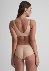 Beige bikini set met een V-hals bralette en bijpassende mid-rise onderkant. Gladde textuur met brede banden en minimale naden voor comfort.