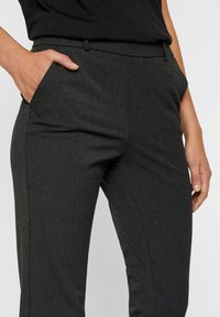 Pantaloni grigi su misura con una vestibilità strutturata, dotati di tasche laterali, una texture liscia e un delicato motivo a spina di pesce.