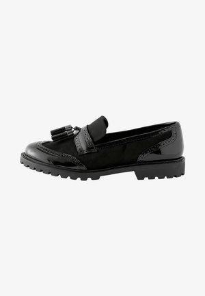 Černé loafers s kombinací semiše a lakované kůže. Detaile s perforacemi ve stylu brogu a kulatým třásním. Silná podešev.