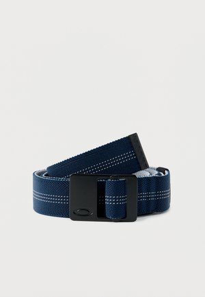 Granatowy pas materiałowy z białymi przeszyciami, czarną prostokątną klamrą i czarnym gumowym zakończeniem z logo, zwinięty na białym tle.