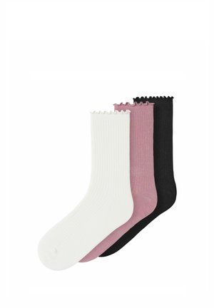 Trois chaussettes côtelées blanches, mauves et noires avec des bords froncés, disposées en chevauchement sur un fond blanc.