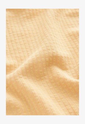 Teksturowana, prążkowana tkanina w miękkim, pastelowym żółtym kolorze. Materiał ma naprzemienne wypukłe paski i gładkie wykończenie.