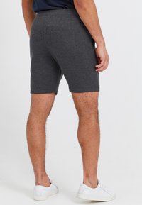 Gray shorts made of soft fabric, with a fitted design, a textured waistband, and back pockets. Worn with white sneakers.