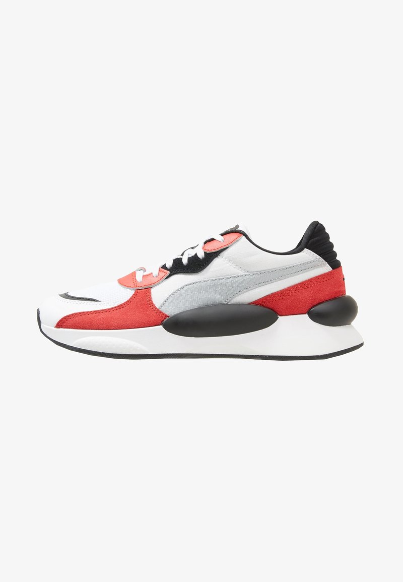 Sneaker featuring a combination of white mesh, red suede, and grey textile, with black accents and large cushioned sole. Classic lace-up design.