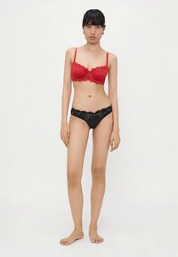 Soutien-gorge push-up en dentelle rouge avec des bretelles réglables et un petit nœud à l'avant, associé à un slip hipster en dentelle noire.
