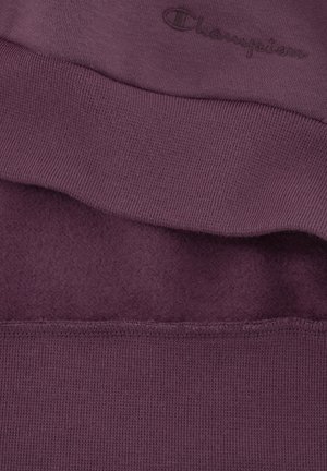 Sweat-shirt violet avec une texture douce, doté de poignets et d'un ourlet côtelés, et d'un logo Champion brodé au niveau du col.