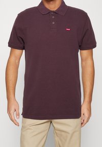 Vínová bavlněná polo košile s klasickým límečkem, tříknoflíkovou légou a malým červeným logem Levi's na levém prsu.