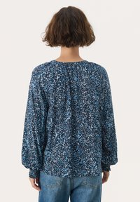 Chemisier à manches longues avec un motif abstrait bleu marine et bleu, en tissu léger, doté d'un détail froncé à l'arrière et de poignets élastiqués.