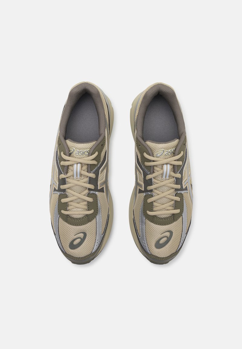 Zapatillas deportivas beige y verde olivo con parte superior de malla transpirable, punta redonda, cordones, acentos plateados y suela acolchada.