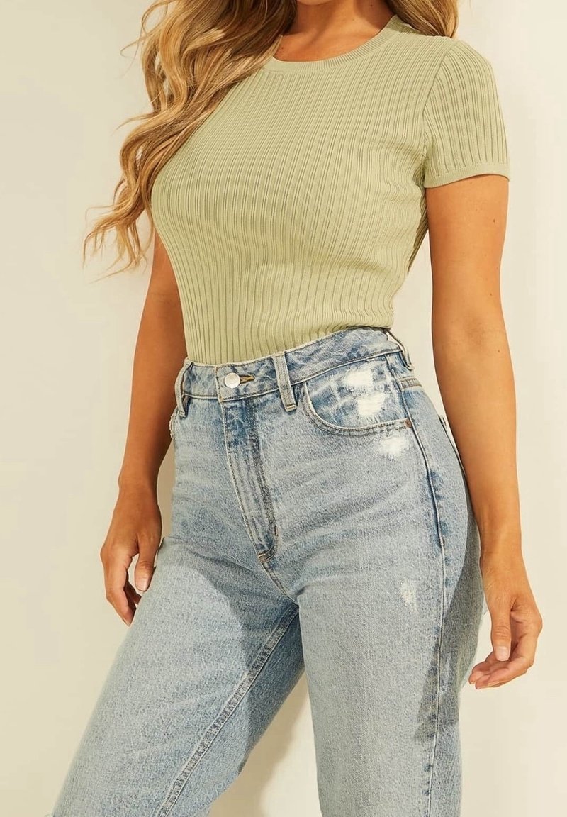 Lyst grøn ribbet kortærmet top parret med slidte lyseblå høj talje jeans, der viser en tætsiddende silhuet og struktureret stof.