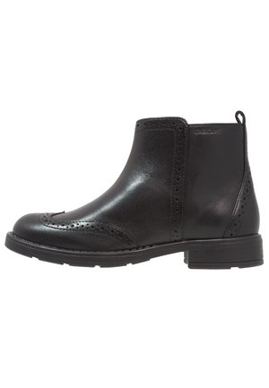 Black leather ankle boot with brogue perforations, low heel, and pull tab at the back, viewed from the inner side.