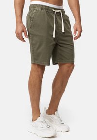 Pantalones cortos verdes oliva fabricados con una mezcla de algodón, con una cintura elástica y cordón blanco, bolsillos laterales y un ajuste casual.
