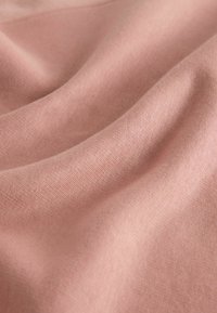 Material roz deschis cu o textură moale și netedă, prezentând falduri delicate și un model de tricotaj uniform pe toată suprafața. Fără accente sau elemente metalice vizibile.