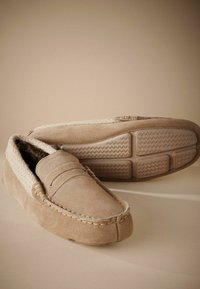 Beżowe zamszowe loafersy z teksturowaną cholewką i miękką podszewką. Posiadają nos moccasin oraz gumową podeszwę z wzorem grip w zygzak.
