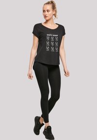 Svart T-skjorte med trykte Darth Vader illustrasjoner og tekst, sammen med svarte leggings og svarte sneakers. Myk stoff, avslappet passform.