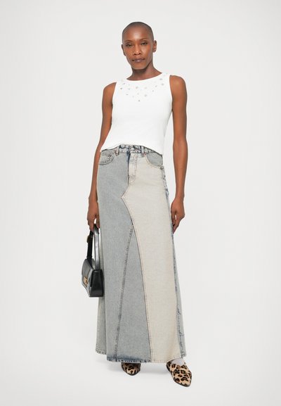 Fehér ujjatlan felső, szegecselt nyakkivágással; aszimmetrikus, világos és sötét árnyalatú farmer maxi szoknya látható varrásokkal; fekete kézi táska.