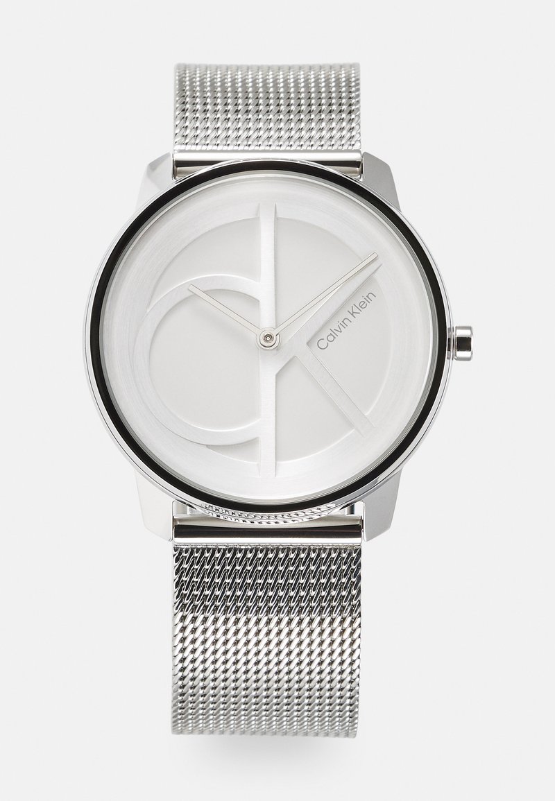 Orologio con cinturino in rete argentata di Calvin Klein, che presenta un quadrante bianco minimalista con un branding sottile e una ghiera nera elegante. Forma rotonda.