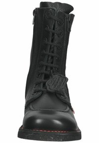 Stivale alla caviglia in pelle nera con lacci frontali, chiusura con zip e cuciture rosse a contrasto lungo la suola. Parte superiore testurizzata e dettaglio del logo.
