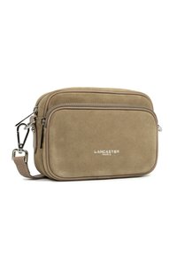 Borsa a tracolla compatta in suede beige con tasca frontale con zip, tracolla regolabile, minuteria in argento e logo "Lancaster Paris" sul fronte.