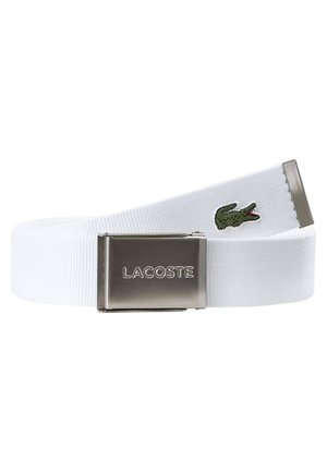 Ceinture en toile blanche avec une boucle rectangulaire en argent, arborant un logo de crocodile vert brodé et une surface texturée.