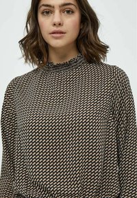 Blusa con motivo in nero, beige e colori pastello. Presenta un collo alto arricciato e maniche lunghe, realizzata in un tessuto leggero.