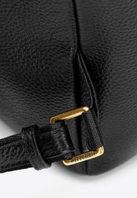 Sac en cuir noir avec une texture, quincaillerie en métal doré et une sangle avec une boucle portant l'étiquette "WITTCHEN."