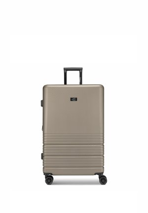 Valigia beige rigida con manico telescopico nero, quattro ruote girevoli e scanalature orizzontali nella metà inferiore.