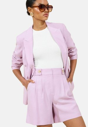Lilac blazer with structured shoulders and two buttons, paired with high-waisted lilac shorts featuring pleats and gold-button accents.