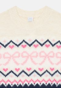 Cremfarbener Strickpullover mit rosa Schleifen, kleinen rosa Herzen und marineblauen Zickzackmustern über der Brust. Rippenbündchen am Rundhalsausschnitt.