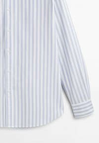 Chemise à manches longues à rayures verticales bleu clair et blanc avec poignets sur fond blanc.