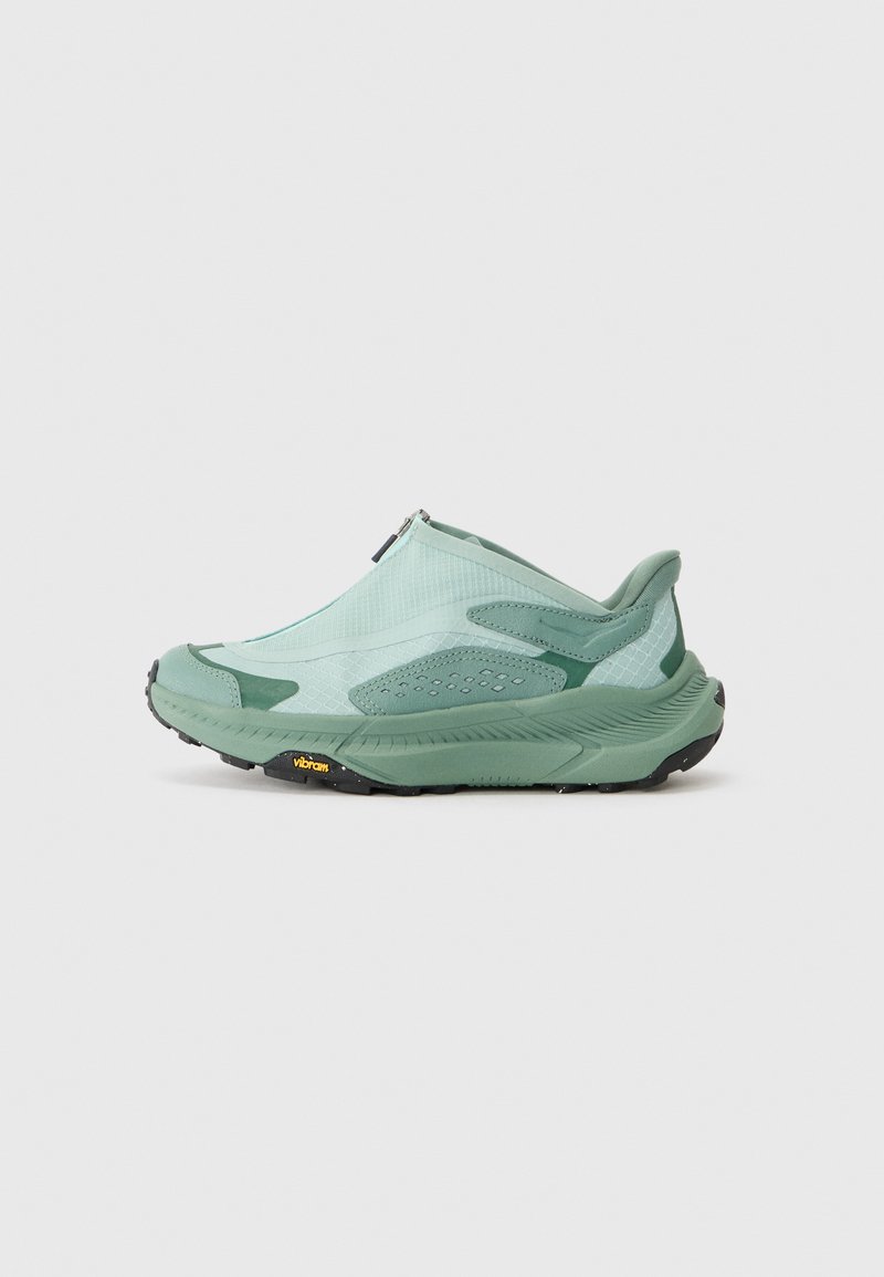 Chaussure verte à enfiler avec une tige en maille texturée, des accents renforcés et une semelle en Vibram noire. Dispose d'une fermeture éclair pour un enfilage facile.